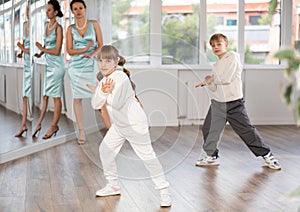 Tween girl and boy rehearsing popping techniques in street dance studio