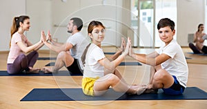Tween girl with brother doing yoga exercises in pair during family workout