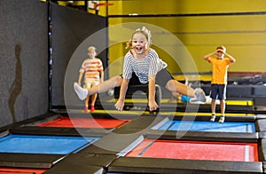 Tween girl doing split in jump in indoor trampoline arena