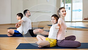 Tween girl with mother doing exercises in pair during family yoga workout