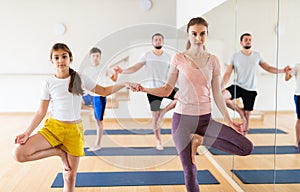 Tween girl with mother doing exercises in pair during family yoga workout