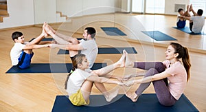 Tween girl with mother doing exercises in pair during family yoga workout