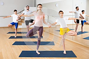 Tween girl with mother doing exercises in pair during family yoga workout