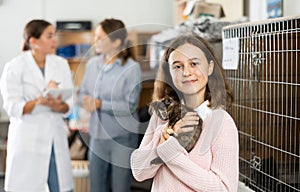 Tween girl standing in animal shelter with little kitten