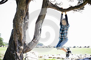 Tween Girl Swinging From Tree Branch