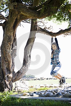 Tween Girl Swinging From Tree Branch