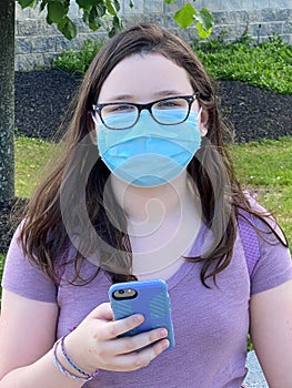 Tween Girl Wearing Surgical Mask Outdoors Holding Mobile Phone