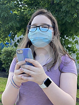 Tween Girl Wearing Surgical Mask Outdoors Holding Mobile Phone