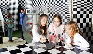Tween girls solving conundrum in quest room stylized under chessboard photo