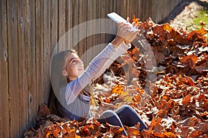 Tween kid girl selfie tablet pc in autumn leaves