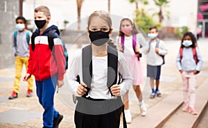 Tween schoolgirl in protective mask going to college on fall day