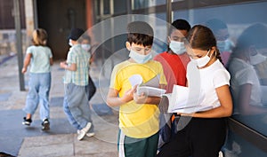 Tweenage schoolchildren in masks talking near school building