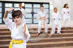 Tweenager mastering karate moves during group class outdoors