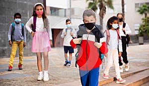 Tweenager in protective mask walking to school campus after lessons photo