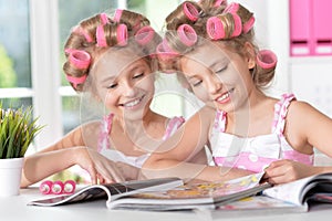Tweenie girls in hair curlers with magazine