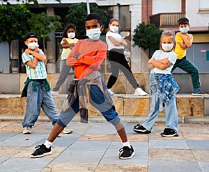 Tweens in protective masks dancing hip-hop on summer street photo