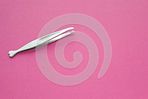 Tweezers stainless steel for women on pink background. Silver pincers for eyebrow plucking