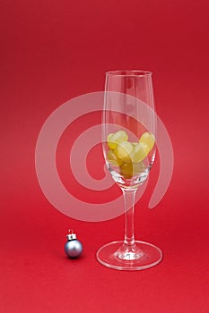 Twelve grapes in a glass for sparkling wine cava. Selective focus, red background, copy space. Spanish traditional to eat twelve