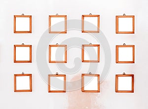 Twelve small simple square wooden frames displayed on a wall