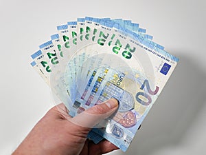 Twenty Euro banknotes fanned out in the hand of a caucasian male against white background. European money.