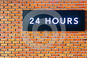 Twenty four hours glowing sign on brick wall