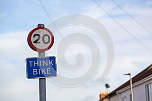 A twenty mile per hour sign with a think bike sign underneath in a street