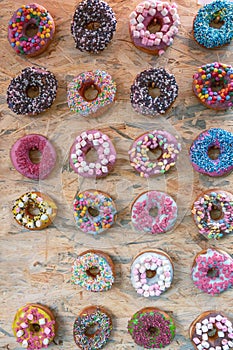 Twenty three donuts with different toppings in many colors and flavors