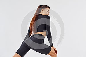 Twerk dancing. Sportive woman in black clothes in the studio against white background