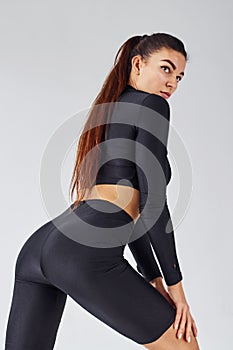 Twerk dancing. Sportive woman in black clothes in the studio against white background