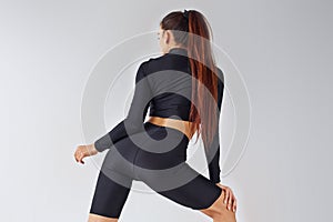 Twerk dancing. Sportive woman in black clothes in the studio against white background