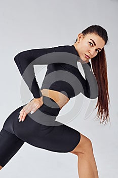 Twerk dancing. Sportive woman in black clothes in the studio against white background