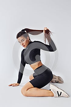 Twerk dancing. Sportive woman in black clothes in the studio against white background