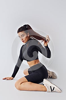 Twerk dancing. Sportive woman in black clothes in the studio against white background