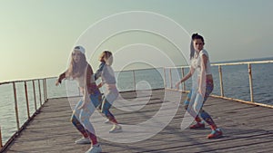 Twerk by young energetic teen girls on a wooden pier near the sea