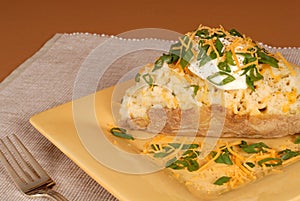 A twice baked potato with scallions, cheese and sour cream photo