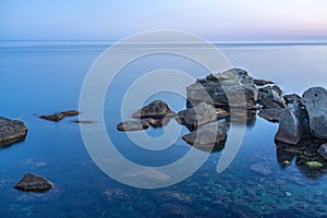 Twilght over the wild rocky beach coastline and the sea. Sea and rocks at night wide angle view