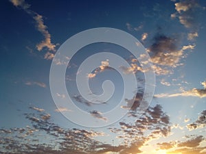 Twilight blue sky with curly white and leaden clouds flying through the atmosphere