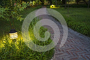 Twilight garden scene with lamp and brick curved road