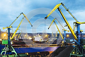 Twilight, Industrial ship, Portal cranes. Loading coal into the holds of a ship at the seaport in Murmansk.