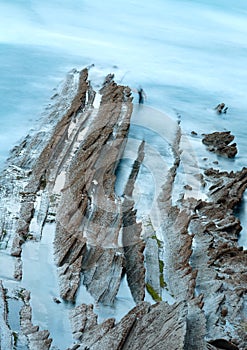 Twilight ocean coast with ribbed stratiform rock.