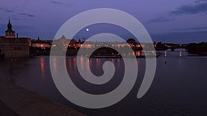 Twilight panorama of Smetana riverbank with National Theater in Prague with traffic and reflection in Vlatava river.