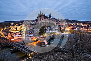 Twilight shot of Hohenzollern Castle in Sigmaringen with the barrage waterfall and reservoir in the background, Germany