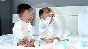 Twin babies crying on bed