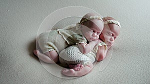 Twin babies sleep in the crib in dresses