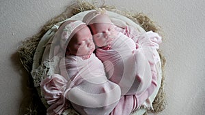 Twin babies sleep in the crib in dresses