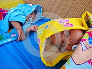 Twin babies sleeping on the beach.