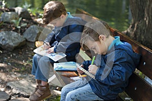 Twin brothers draw with pens in notebooks