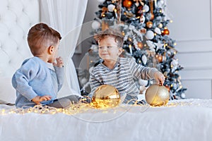 Twin brothers in front of the christmas tree with candles and gifts. love, happiness and big family concept