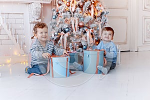 Twin brothers in front of the christmas tree with candles and gifts. love, happiness and big family concept