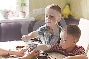 Twin brothers helping her mother to grind coffee